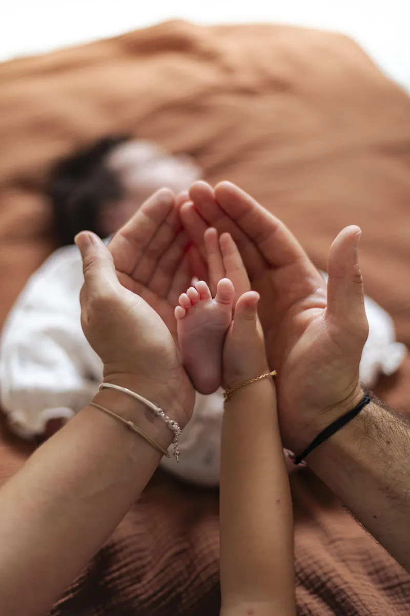 Mains des parents enveloppant les pieds de leur nouveau-né
