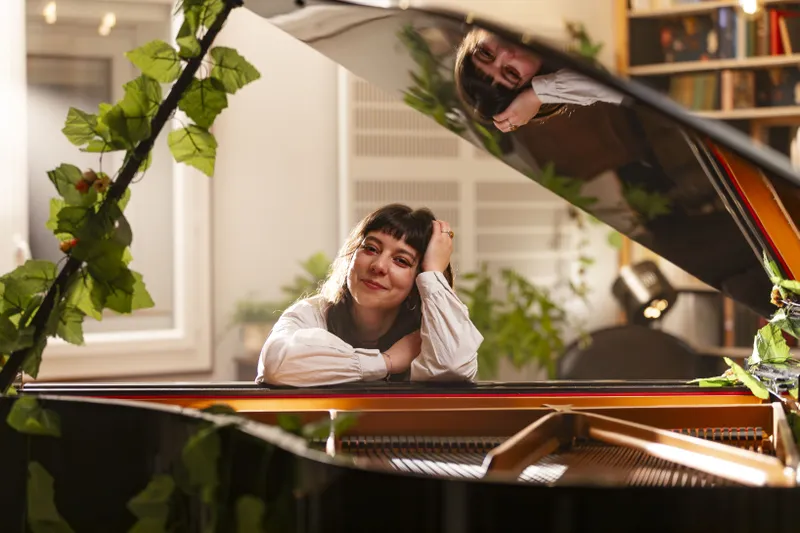 Musicienne accoudée sur un piano à queue dans un intérieur élégant