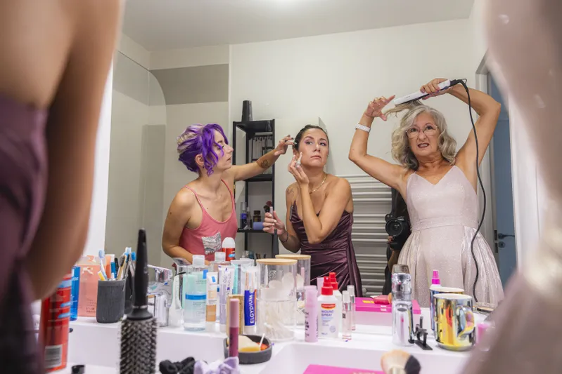 Préparatifs de mariage avec trois femmes se coiffant et se maquillant devant le miroir