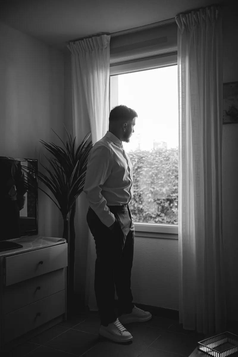 Portrait en noir et blanc du marié regardant par la fenêtre