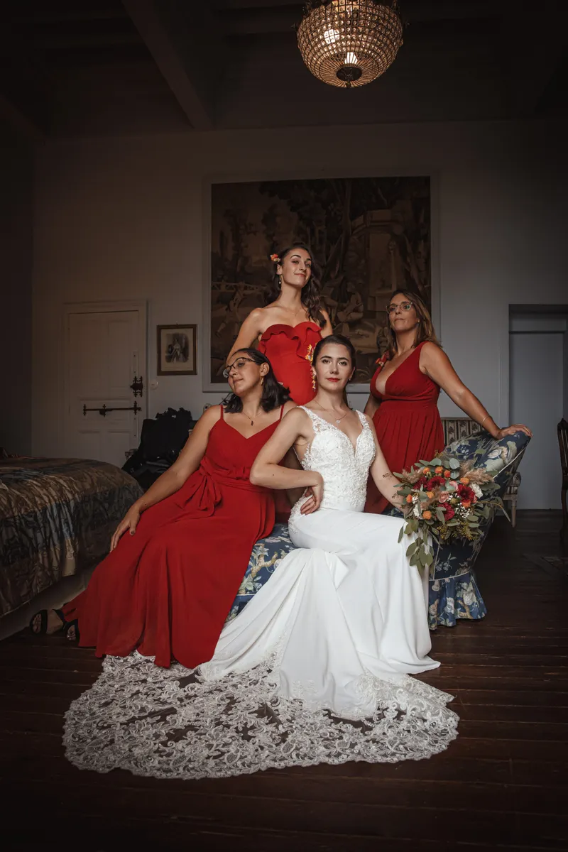 Mariée posant avec ses demoiselles d'honneur en robes rouges dans un château