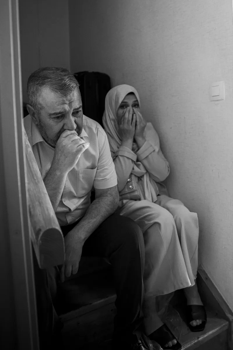 Parents émus assis dans un couloir avant le mariage de leur fille, noir et blanc