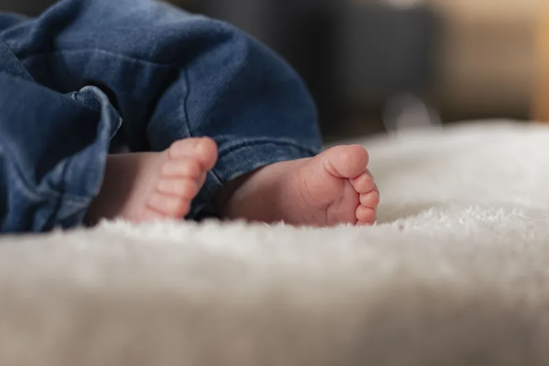 Gros plan sur les petits pieds d'un nouveau-né en jean sur une couverture douce