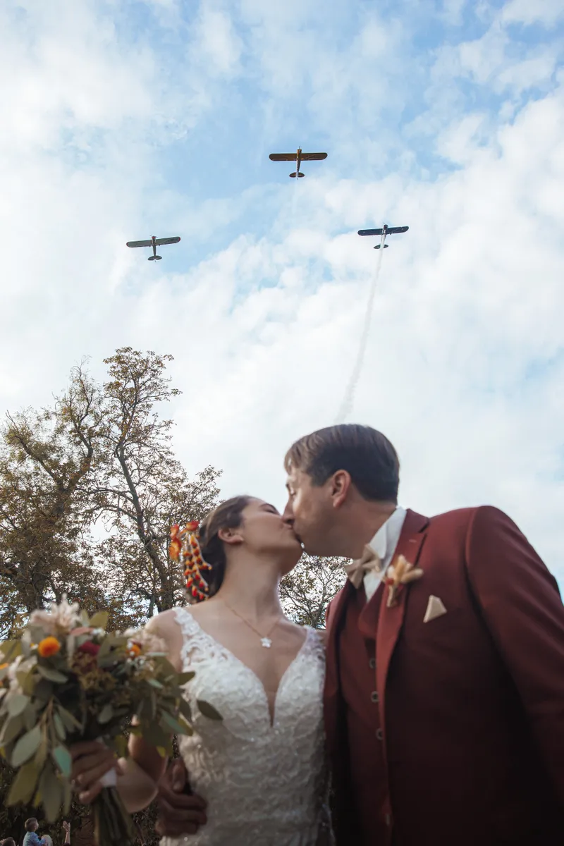 Mariés s'embrassant sous un passage d'avions lors de leur mariage en plein air