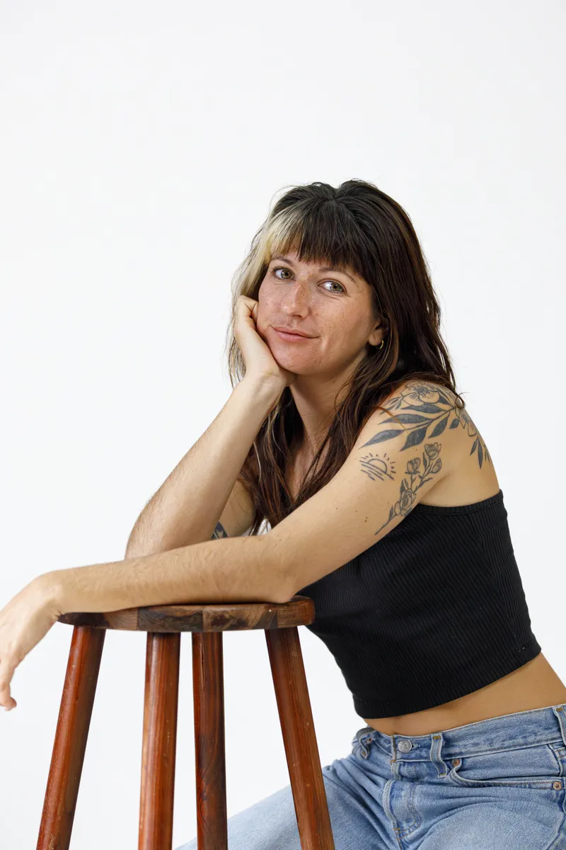 Portrait d'une comédienne souriante accoudée à un tabouret