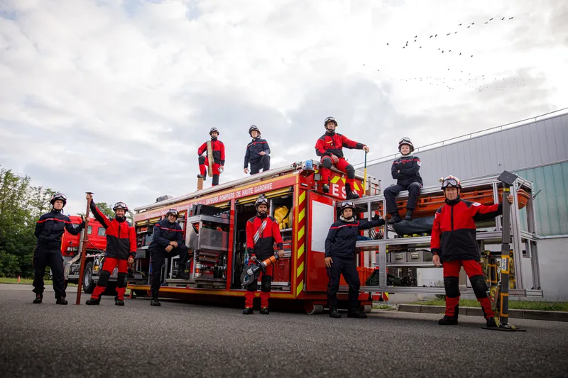 Équipe de pompiers en tenue d'intervention posant sur un camion grande échelle