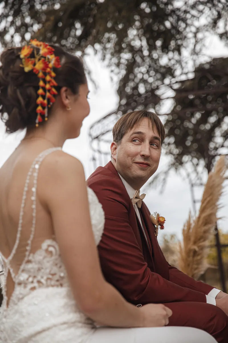 Marié en costume bordeaux regardant tendrement la mariée lors de la cérémonie