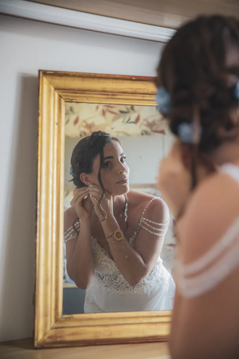 Mariée ajustant ses boucles d'oreilles devant un miroir doré