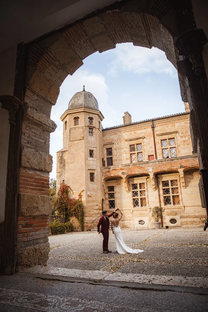 Mariée dansant avec le marié sous une arche de château en pierre