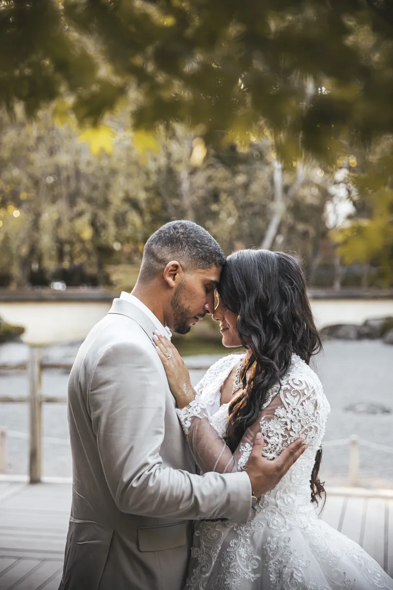 Couple de mariés front contre front dans un parc au bord de l'eau