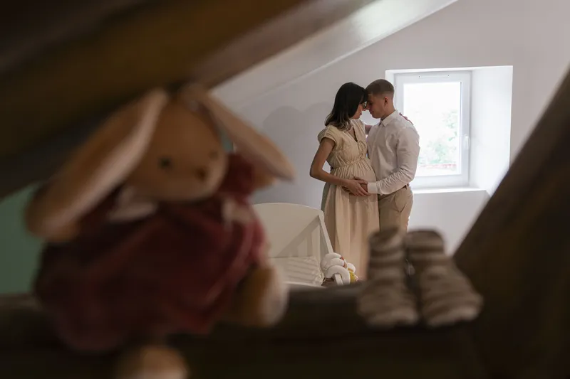 Couple de futurs parents enlacés dans la chambre du bébé avec un lapin en peluche