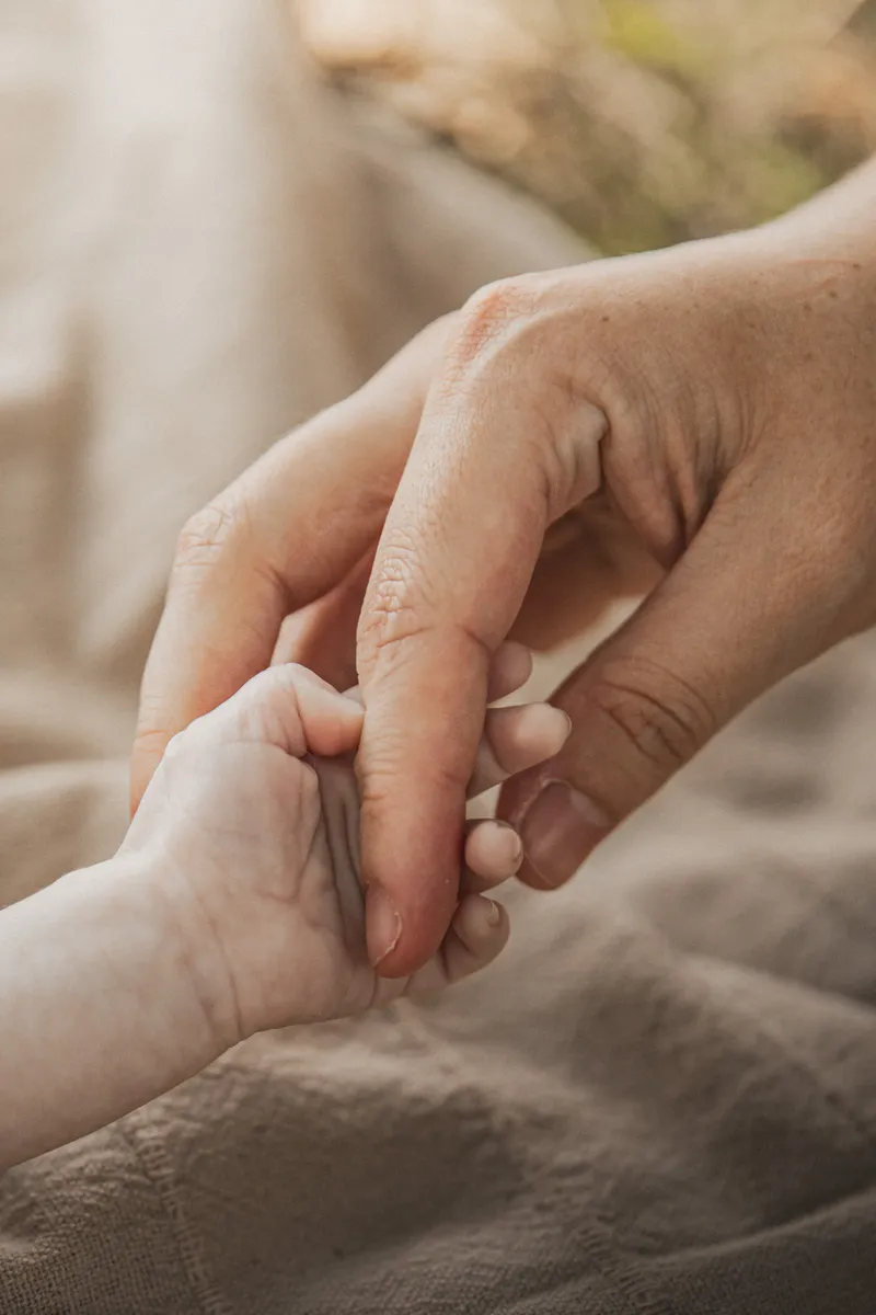 Main d'adulte tenant délicatement la main d'un tout-petit