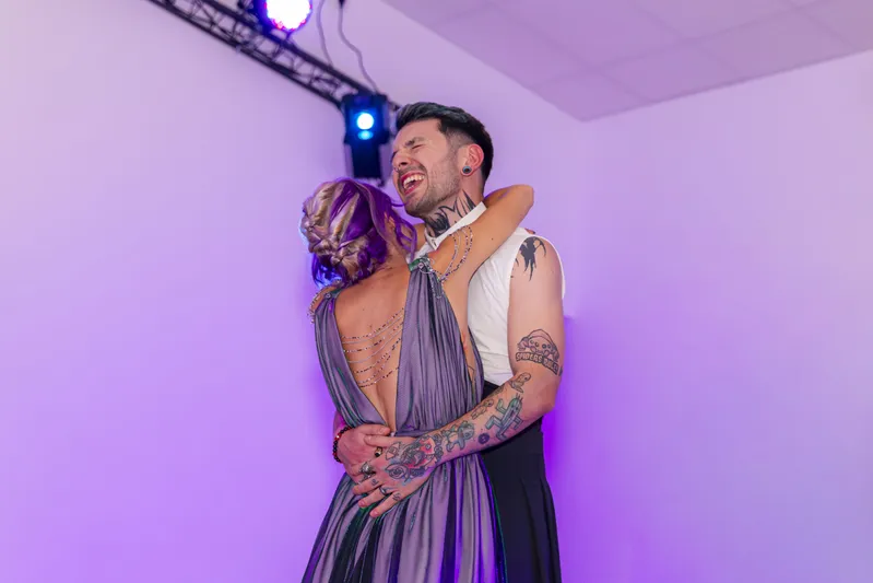 Couple de mariés dansant enlacés sous un éclairage violet