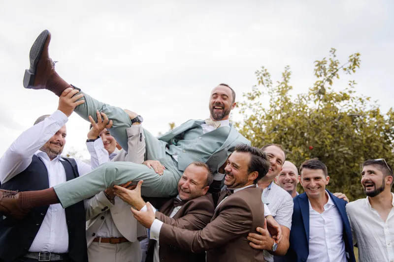 Marié porté en triomphe par ses amis lors d'un mariage en plein air