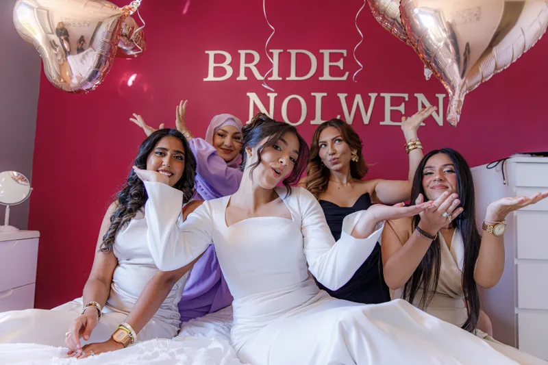 Mariée posant avec ses amies sur un lit décoré de ballons BRIDE