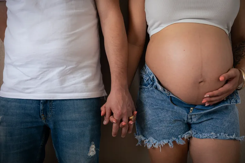 Couple attendant un bébé posant main dans la main, gros plan sur le ventre