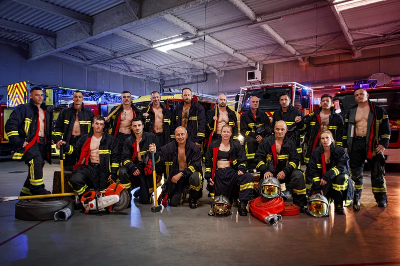 Photo de groupe des pompiers en tenue ouverte posant dans le garage de la caserne