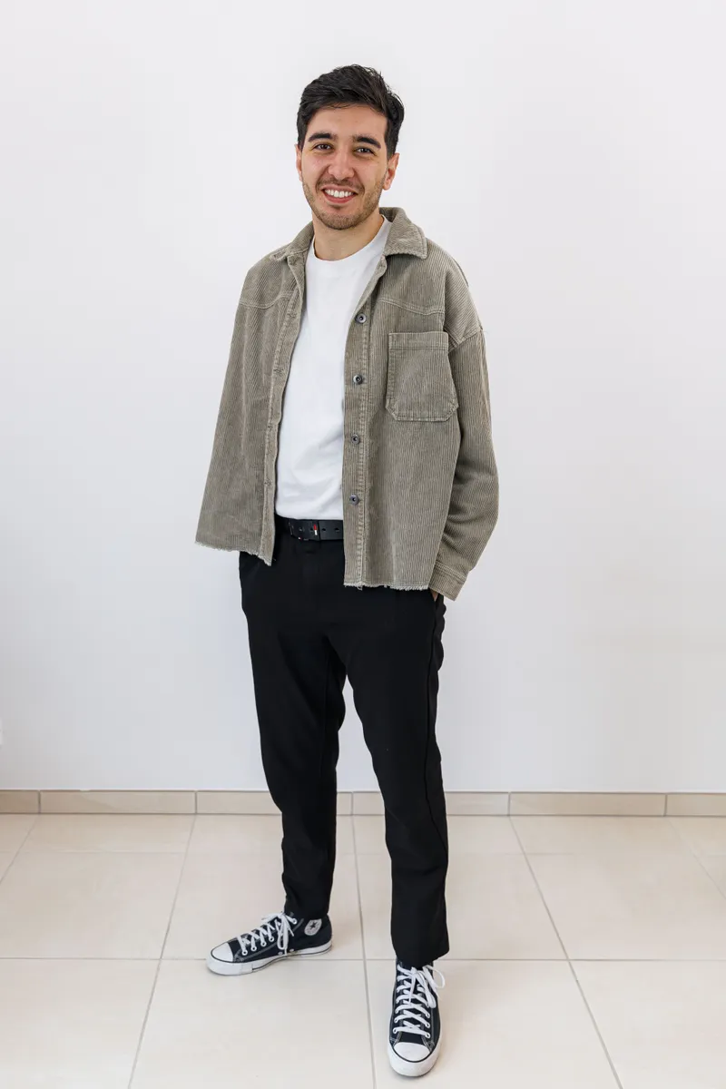 Portrait en pied d'un comédien souriant en chemise et baskets sur fond blanc