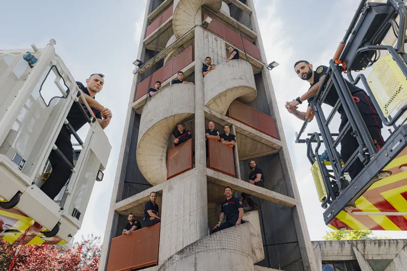 Pompiers posant dans un escalier hélicoïdal de la tour d'entraînement entre deux camions