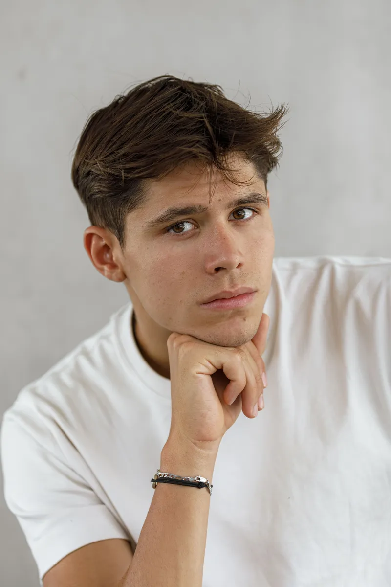 Portrait pensif d'un jeune comédien en t-shirt blanc le menton sur le poing