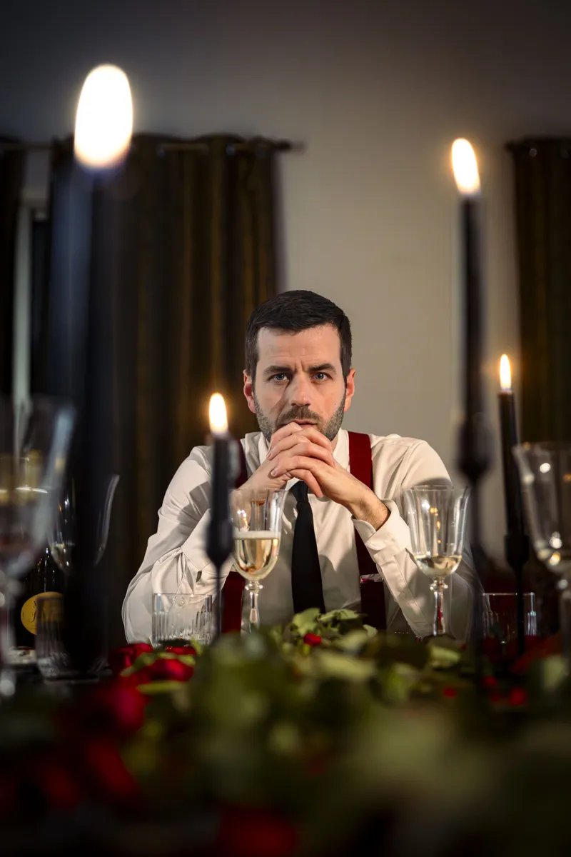 Homme élégant assis à une table décorée de bougies et verres à vin