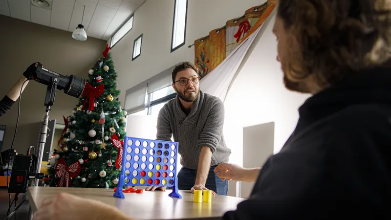 Comédien jouant au Puissance 4 dans un décor de Noël sur un tournage