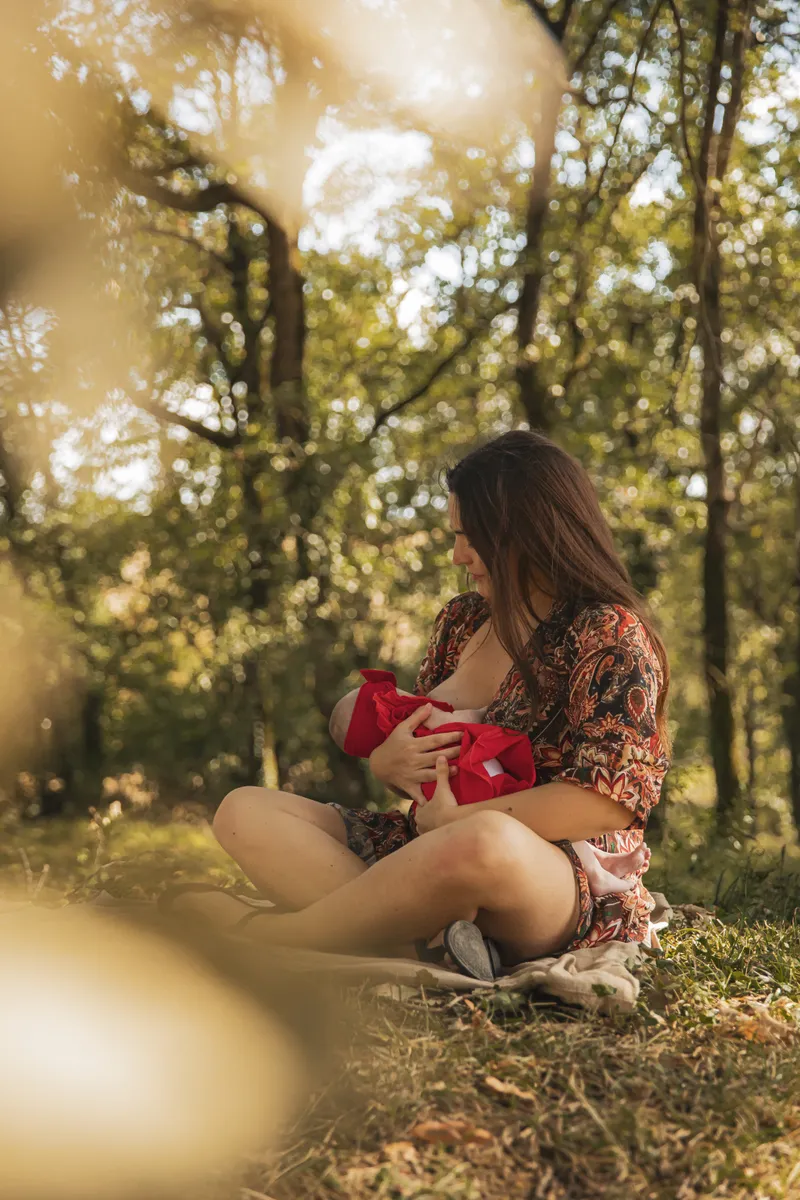 Maman berçant son bébé sous les arbres en lumière naturelle